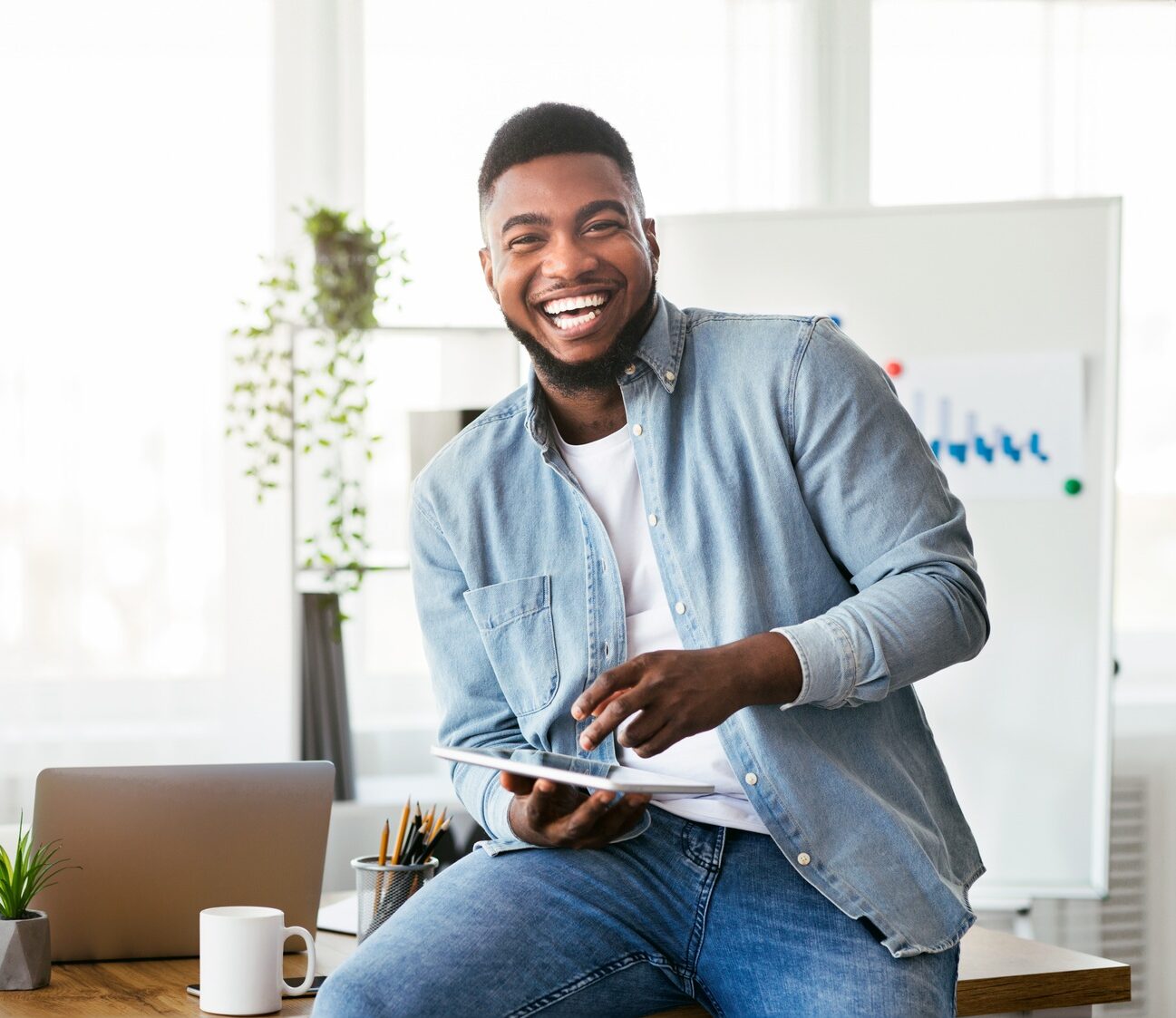 Cheerful black employee using digital tablet in office and laughing
